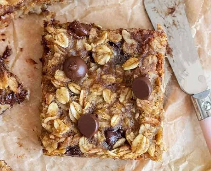 Delicious banana oatmeal bars on a wooden table with fresh bananas