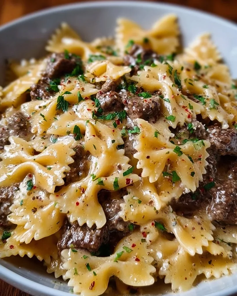 Creamy Parmesan garlic beef bowtie pasta dish garnished with herbs