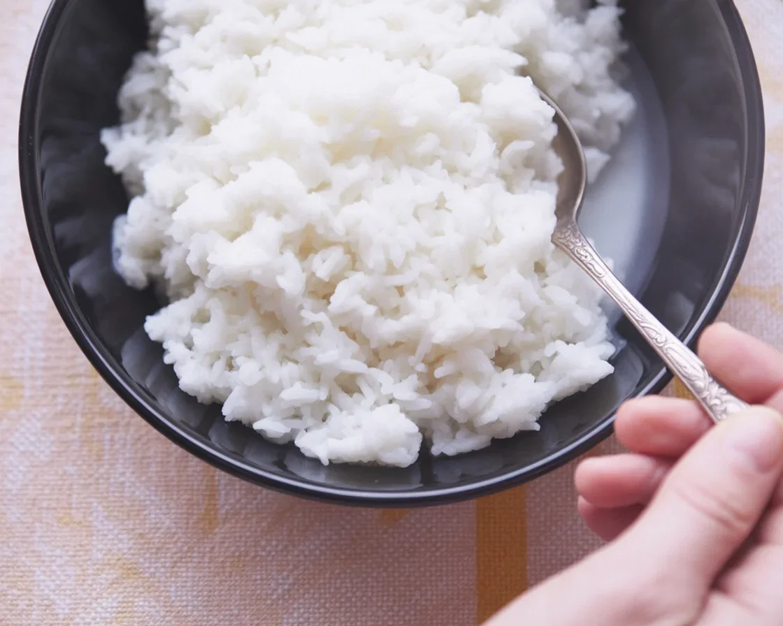 Cooked fluffy white rice in a pot with water and steam.