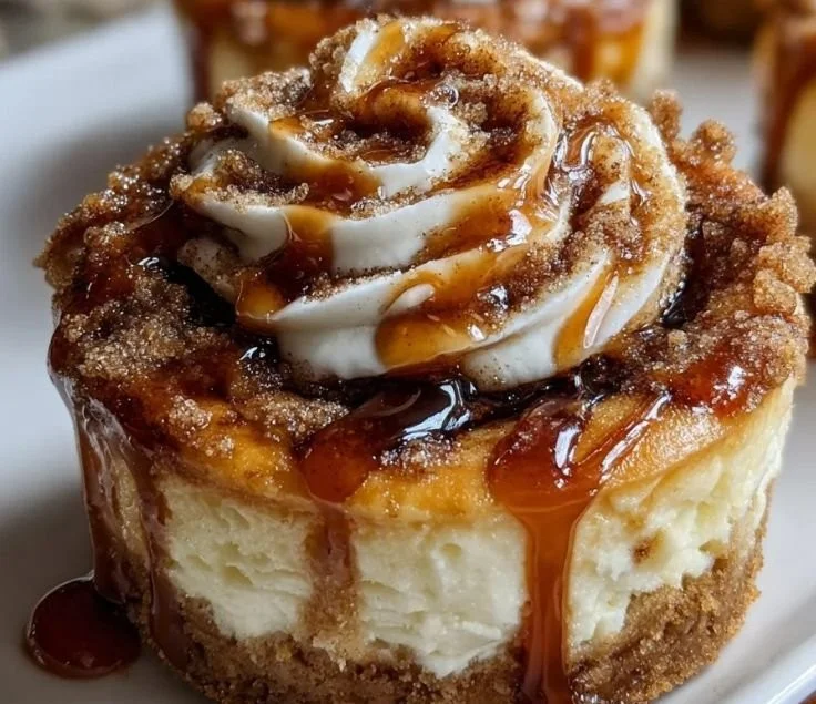 Mini cinnamon roll cheesecakes topped with swirls of cinnamon and cream cheese.