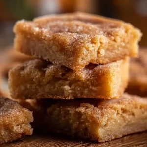 Batch of Cinnamon Sugar Blondies on a plate with a sprinkle of cinnamon sugar on top