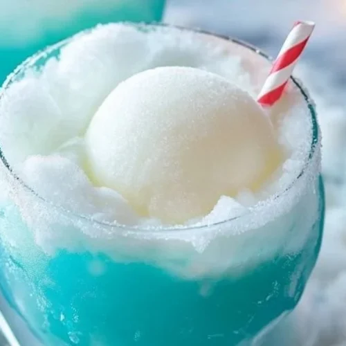 A refreshing Frozen Snowball Punch in a glass, garnished with fruit.